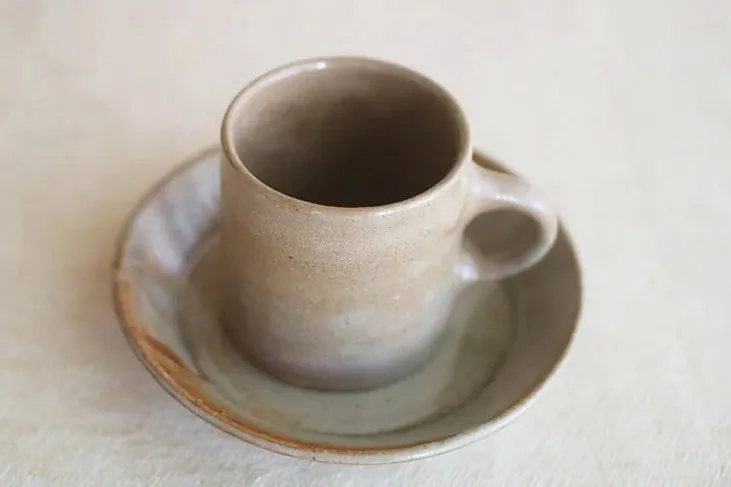 ソーサーにのせたグレーがかった陶器のカップ